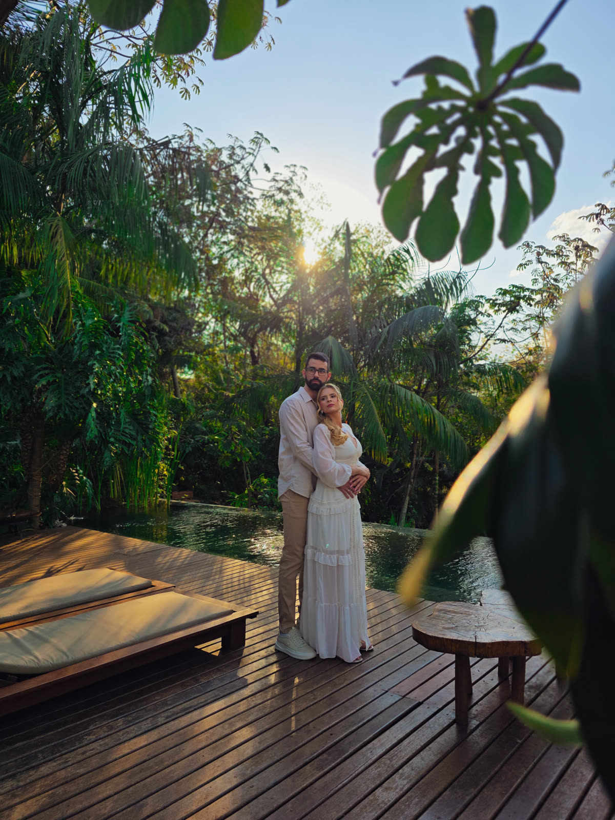 Casal abraçado à beira de piscina ao entardecer